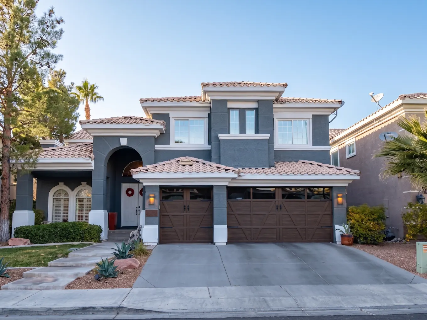 Two story home with a slate blue stucco exterior and white trim after a full repaint