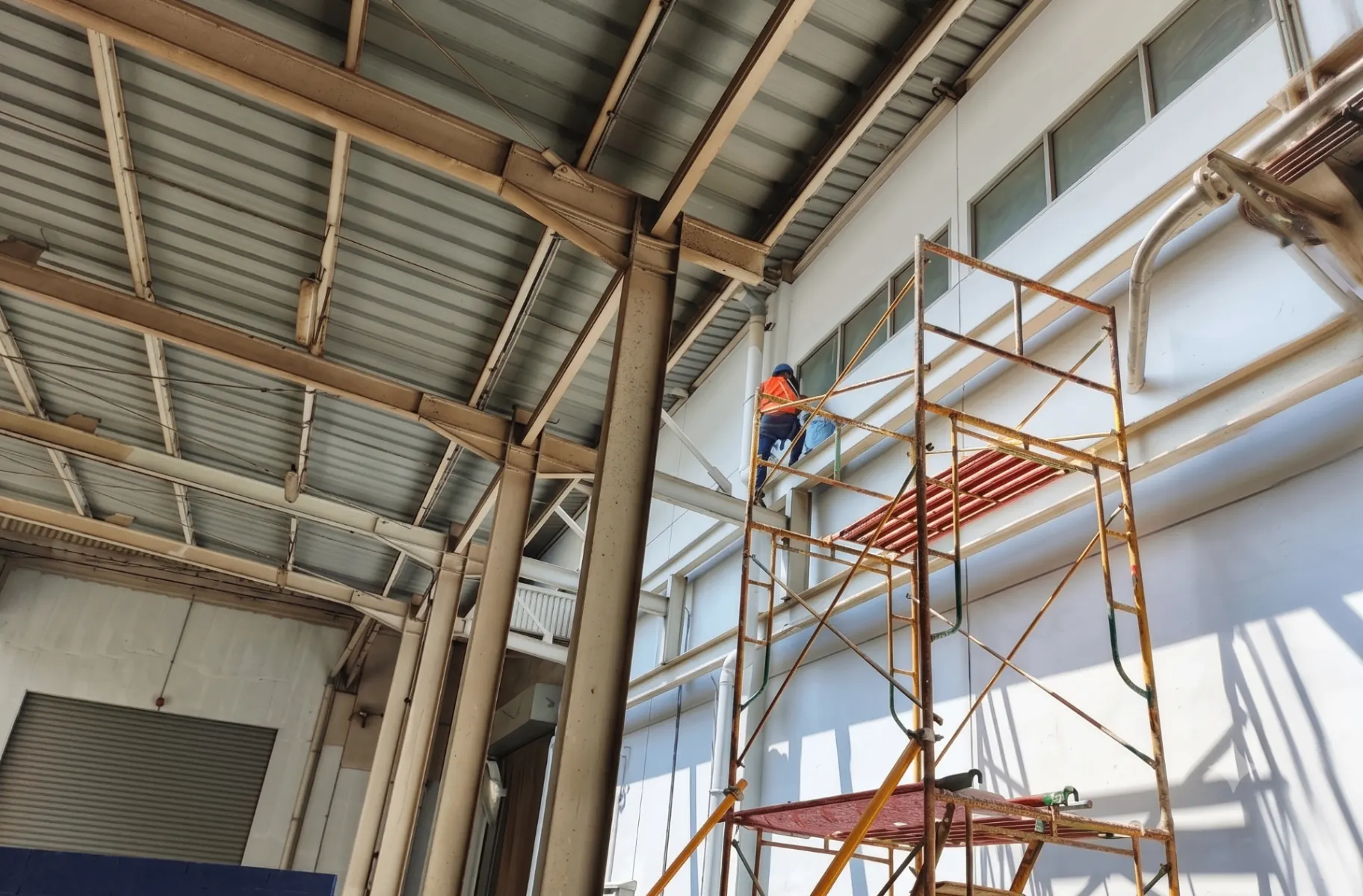 Color Drop painter on scaffolding inside a commercial warehouse